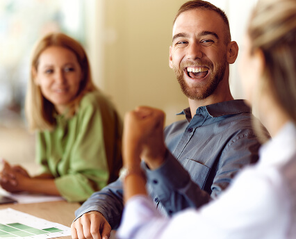 A group of people. A man is laughing with a person who is facing away from camera