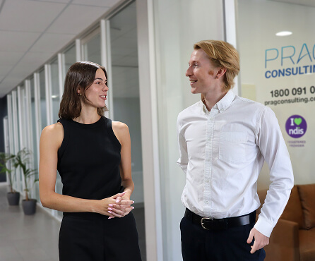 A man and woman outside the Prag Consulting office, smiling and facing each other