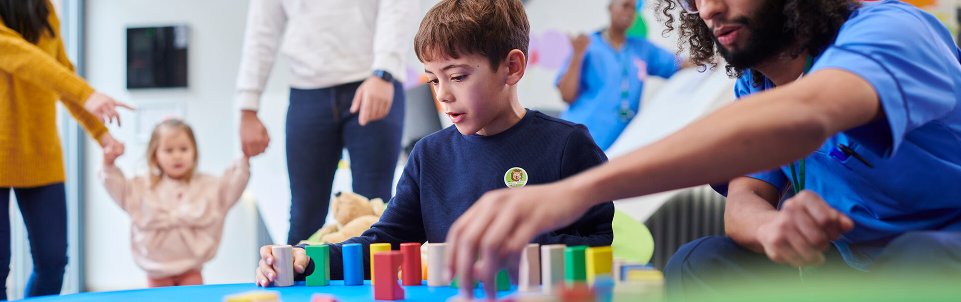 A child playing with building blocks, assisted by an adult